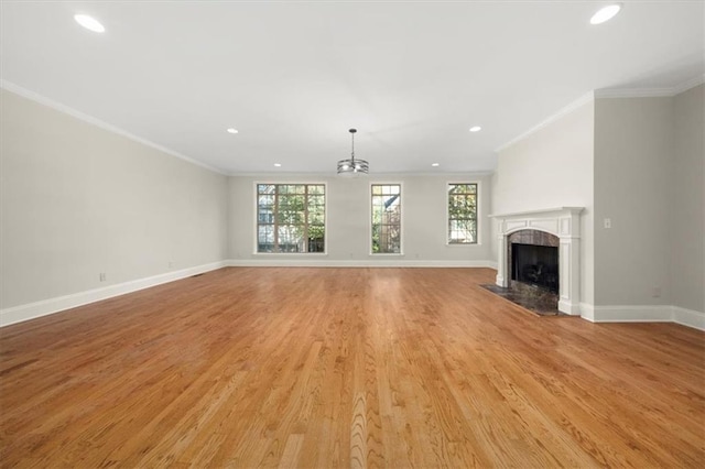 unfurnished living room with a fireplace, light hardwood / wood-style flooring, ornamental molding, and a notable chandelier