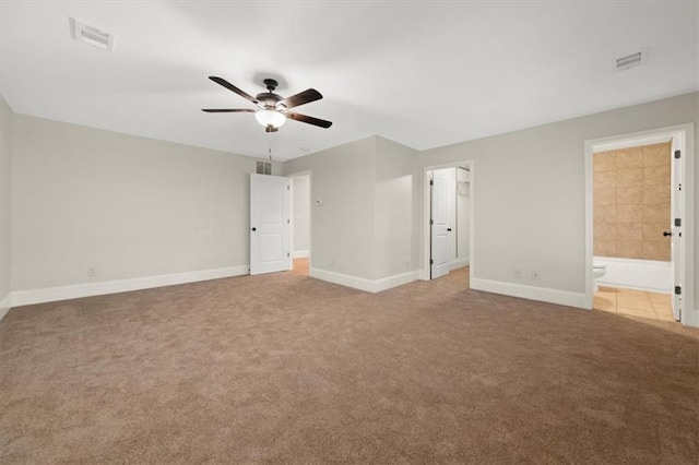 unfurnished bedroom with ceiling fan, light colored carpet, and connected bathroom