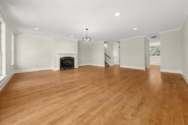 unfurnished living room featuring a fireplace, light hardwood / wood-style floors, a chandelier, and ornamental molding