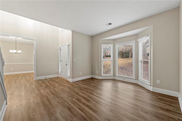 unfurnished room with hardwood / wood-style flooring and a notable chandelier