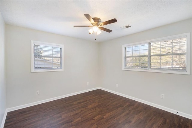 spare room featuring dark wood-style flooring, healthy amount of natural light, baseboards, ceiling fan, and a textured ceiling