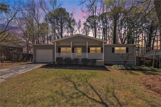 single story home featuring a porch, a garage, driveway, and a lawn