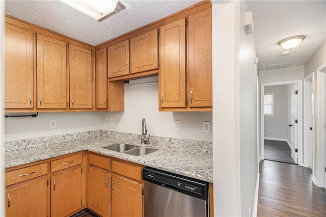 kitchen featuring stainless steel dishwasher, a sink, a textured ceiling, dark wood-style floors, and baseboards