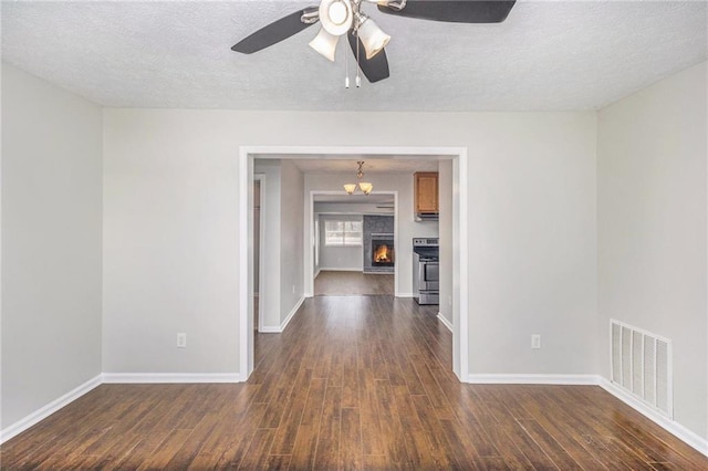 empty room with dark wood finished floors, baseboards, a textured ceiling, and ceiling fan