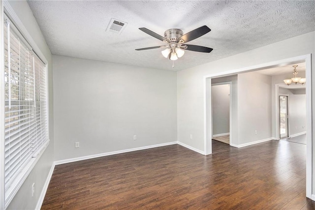 unfurnished room featuring dark wood-style flooring, ceiling fan, baseboards, a textured ceiling, and a chandelier