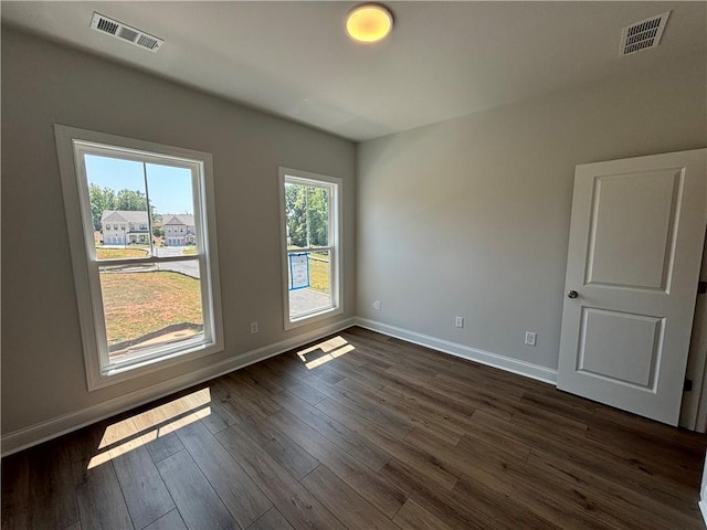 spare room featuring a wealth of natural light and dark hardwood / wood-style flooring