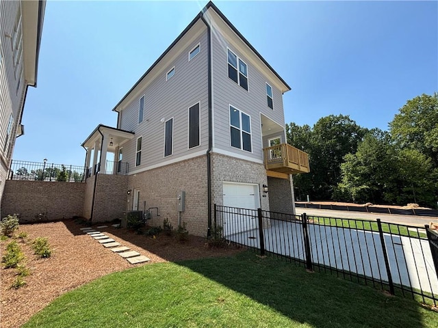 view of side of home featuring a yard, a balcony, and a garage