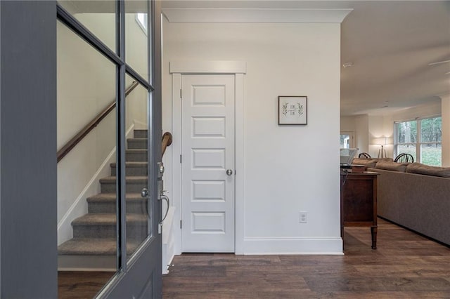 foyer with stairs, baseboards, and dark wood finished floors