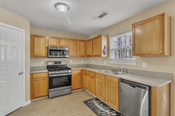 kitchen featuring visible vents, stainless steel appliances, light countertops, and a sink