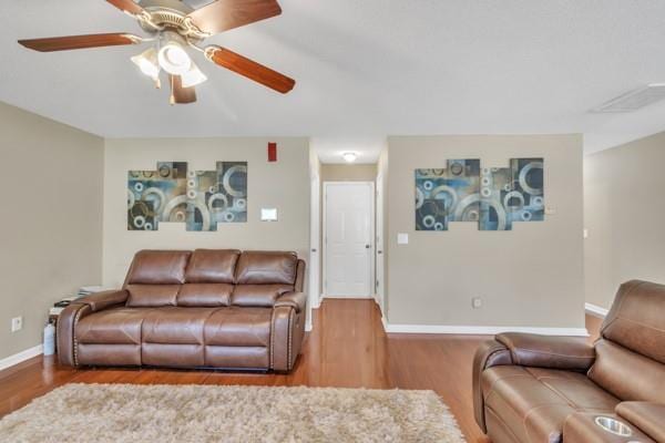 living room with visible vents, baseboards, a ceiling fan, and wood finished floors
