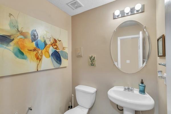 bathroom featuring toilet, a sink, and visible vents