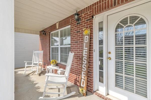 doorway to property featuring brick siding and covered porch