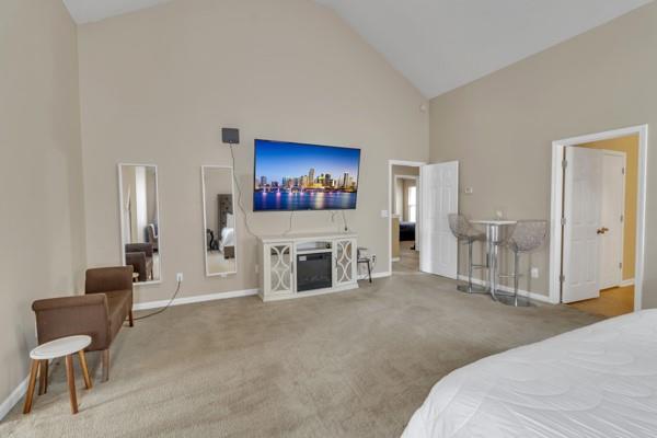 bedroom featuring baseboards, carpet floors, and high vaulted ceiling