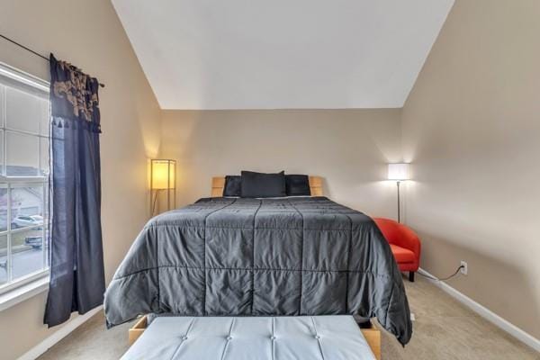 carpeted bedroom featuring lofted ceiling and baseboards