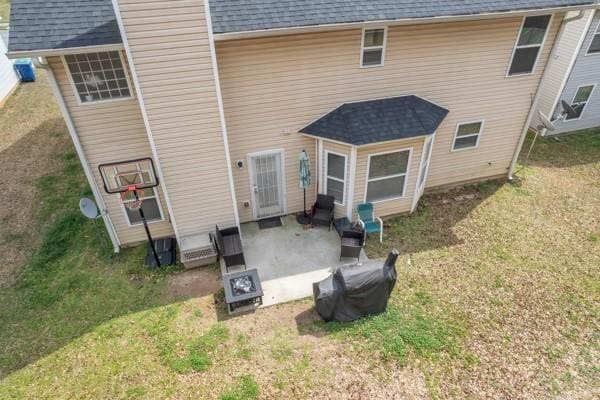 back of house featuring a lawn, a patio area, and a shingled roof