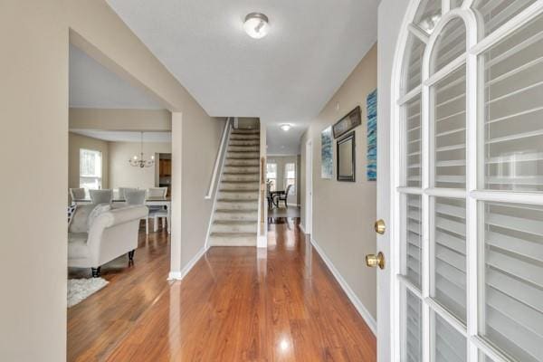 entryway with stairway, a wealth of natural light, wood finished floors, and baseboards
