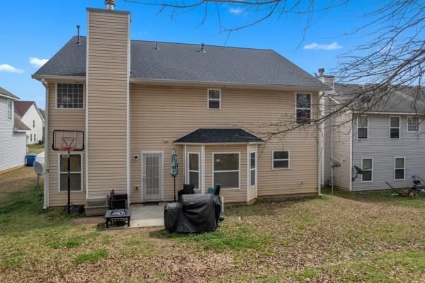 back of house with a chimney, a yard, and a patio area