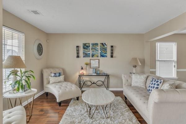 living room featuring baseboards, dark wood-type flooring, and visible vents