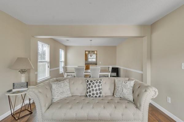 living room with wood finished floors, baseboards, and a notable chandelier