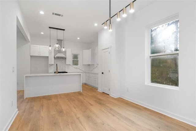 kitchen featuring pendant lighting, white cabinets, an island with sink, sink, and stainless steel dishwasher