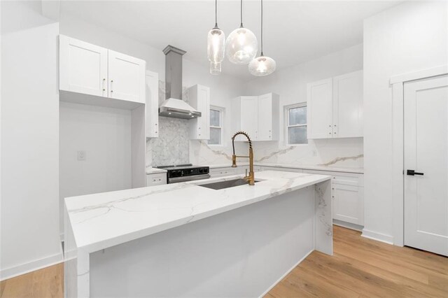 kitchen featuring tasteful backsplash, black range with electric cooktop, sink, white cabinets, and an island with sink