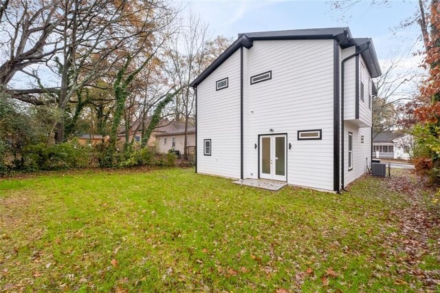 back of property with central AC unit and a lawn