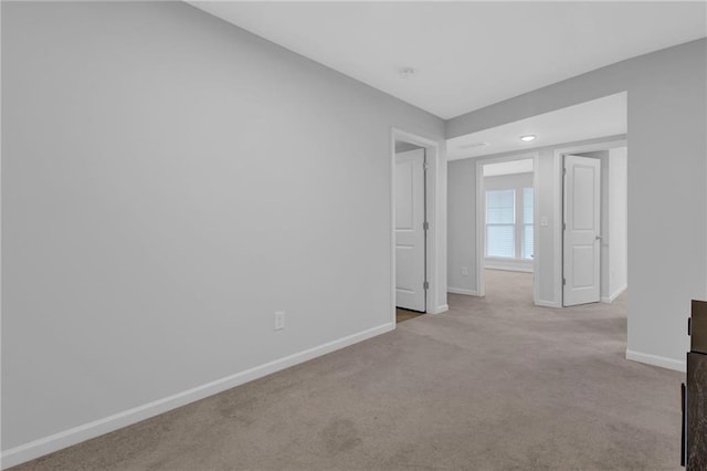 spare room with baseboards and carpet floors