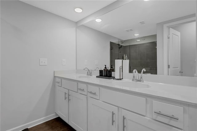 full bathroom featuring visible vents, a sink, a shower stall, double vanity, and baseboards