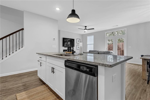 kitchen with pendant lighting, a sink, stone countertops, stainless steel dishwasher, and wood finished floors