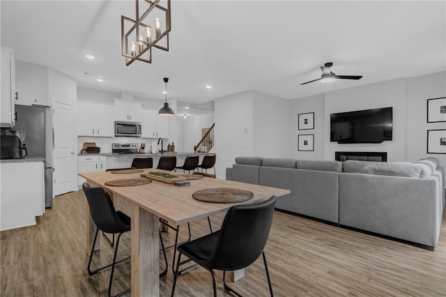 dining area featuring recessed lighting, a ceiling fan, light wood-style flooring, and stairs