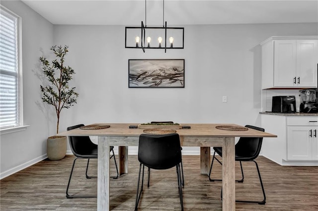 dining space featuring a notable chandelier, dark wood-style floors, and baseboards