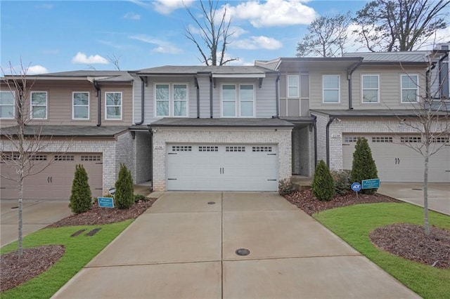 townhome / multi-family property featuring brick siding, an attached garage, and driveway