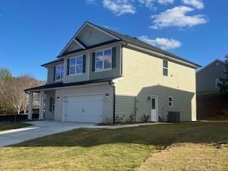 exterior space with a lawn, cooling unit, and a garage