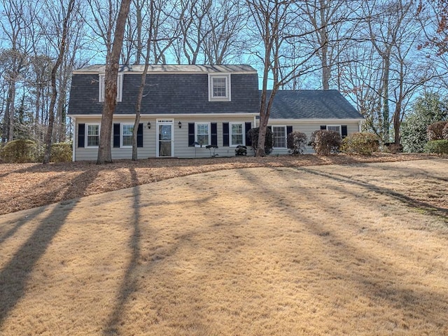 view of front facade featuring a front lawn, roof with shingles, and a gambrel roof