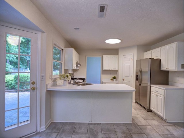 750 Whitehall Way, Roswell, GA 30076 - kitchen with a peninsula, stainless steel fridge, white cabinetry, light countertops, and a textured ceiling