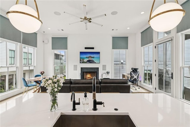 kitchen featuring a lit fireplace, decorative light fixtures, open floor plan, a ceiling fan, and recessed lighting