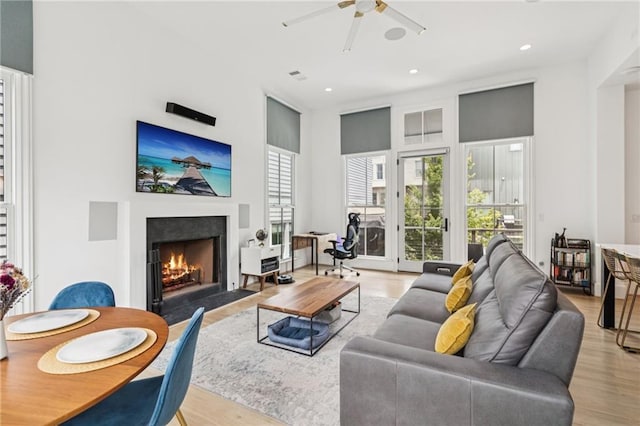 living room with a fireplace with flush hearth, a ceiling fan, light wood-style flooring, and recessed lighting