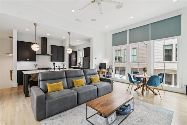 living room with a ceiling fan, light wood-style floors, and recessed lighting