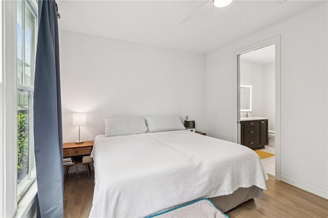 bedroom with light wood finished floors and connected bathroom
