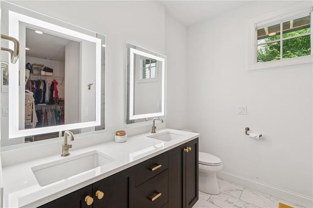 bathroom featuring marble look tile flooring, double vanity, and a walk in closet