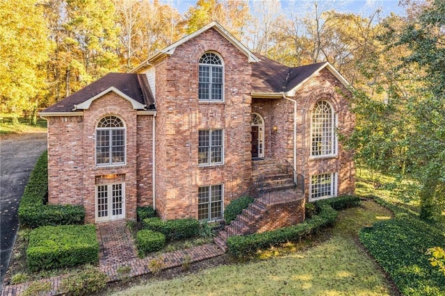 view of front of property featuring brick siding, stairs, and french doors