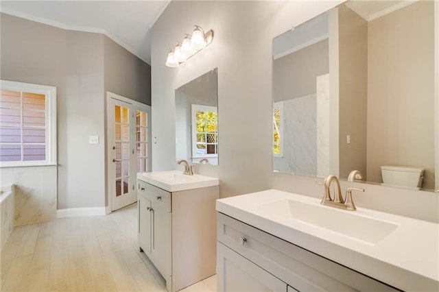 full bath with two vanities, wood finished floors, crown molding, and a sink