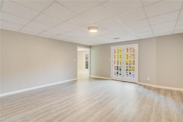 unfurnished living room with baseboards, a paneled ceiling, and wood finished floors