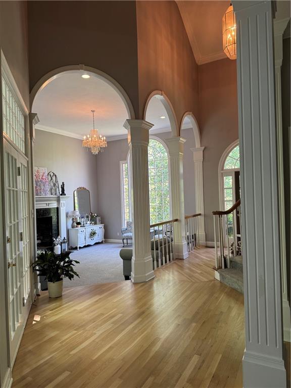 interior space featuring wood finished floors, a high ceiling, an inviting chandelier, baseboards, and decorative columns