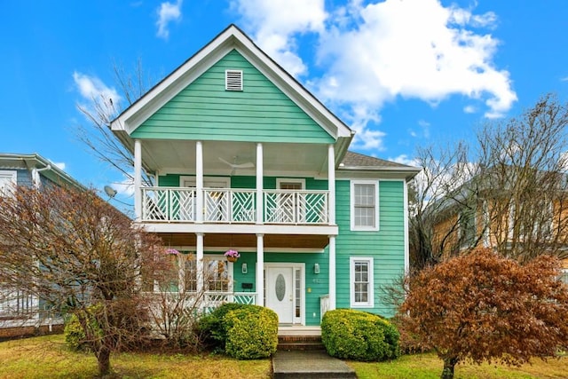 view of front of house with ceiling fan, a front yard, a balcony, and a porch