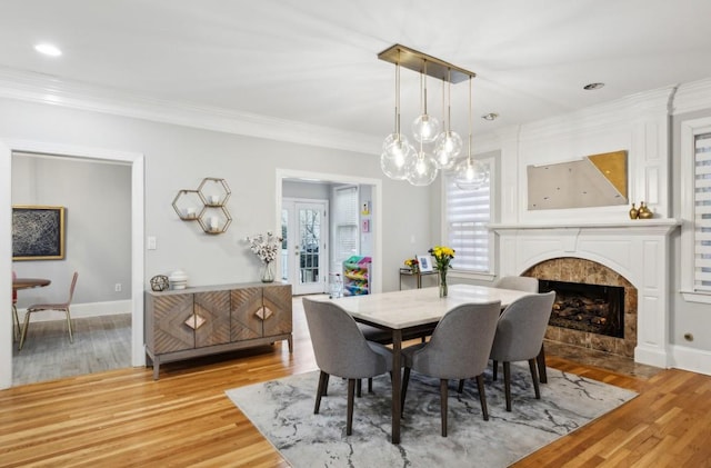 dining area featuring ornamental molding, a fireplace, and light hardwood / wood-style floors