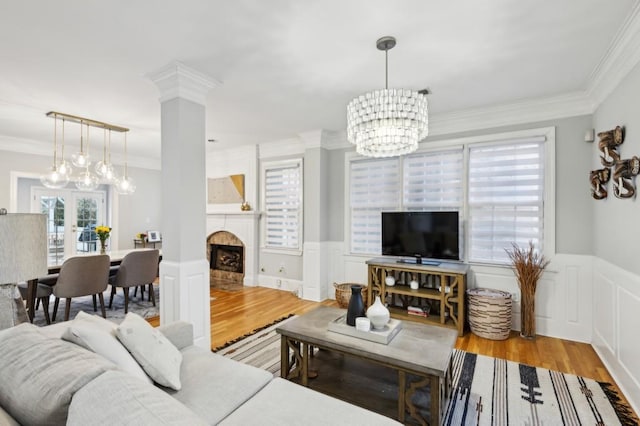 living room with crown molding, a chandelier, light wood-type flooring, and french doors