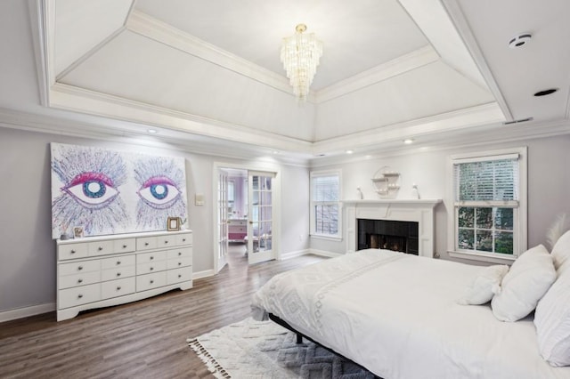 bedroom featuring an inviting chandelier, a tray ceiling, wood-type flooring, and ornamental molding