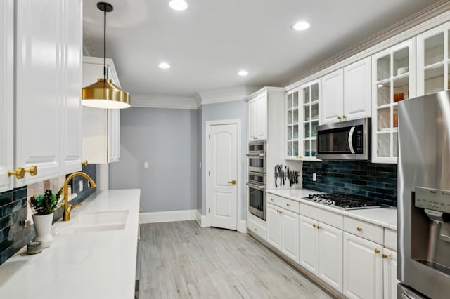 kitchen featuring sink, white cabinetry, hanging light fixtures, ornamental molding, and stainless steel appliances