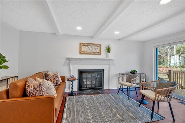 unfurnished living room featuring wood-type flooring, a textured ceiling, and beam ceiling